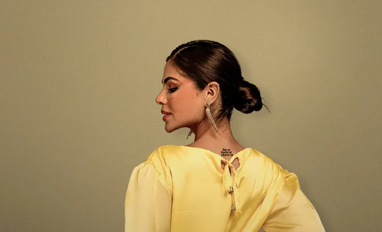 Catarina Leal de blusa amarela, de costas, olhando para o lado