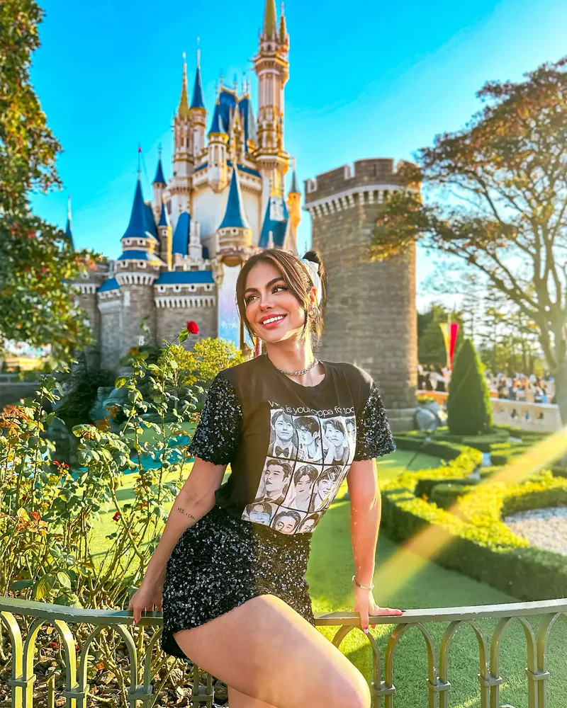 Depois do preset: Catarina sorrindo, sentada numa grade com um castelo ao fundo