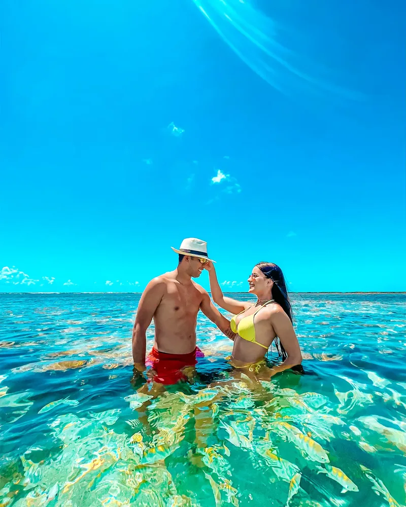 Depois do preset: casal dentro do mar cristalino, água verde e céu azul forte