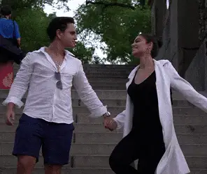 Catarina e um rapaz de mãos dadas descendo uma escadaria