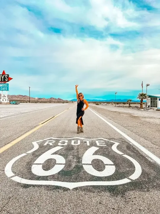 Mulher de braço erguido no meio da estrada, sobre a pintura da Rota 66